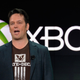 Head of Xbox Phil Spencer stands in front of an Xbox sign wearing a State of Decay shirt.